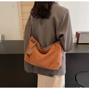 Détail du sac cabas en daim marron avec bandoulière et étiquette rectangulaire