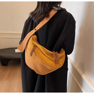 Detail of yellow crescent crossbody bag with thick woven shoulder strap and buckle