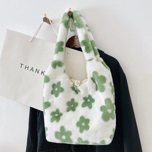 Dettaglio borsa tote in peluche bianca con motivo a fiori verdi appesa a un gancio