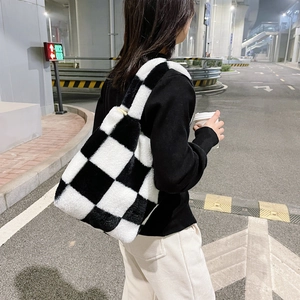 Chic black and white checkerboard plush handbag shown in a trendy urban night setting