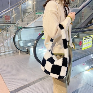 Detail of checkered plush shoulder bag with wide strap on a model in a casual setting