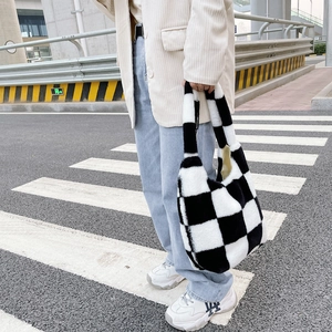 Sac à main chic en peluche à damier noir et blanc porté par un mannequin en ville