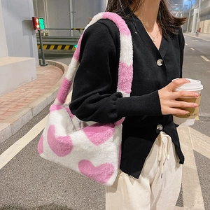 Détail d'un sac à épaule en peluche douce avec motif coeur rose en scène de street style