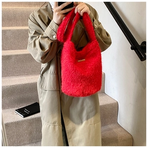 Détail d'un sac seau en fausse fourrure rouge duveteuse avec étiquette en cuir sur manteau