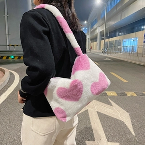 Détail du sac à bandoulière en peluche blanche avec motifs cœurs roses porté en ville