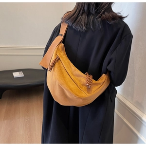 Detail of ginger yellow crescent crossbody bag featuring suede texture and woven zip puller