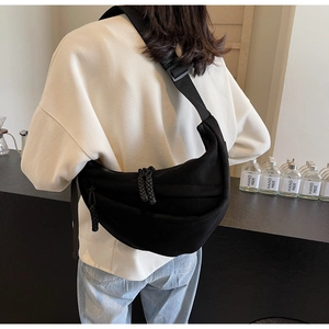 Detailed view of black canvas crescent crossbody bag with adjustable strap worn by model