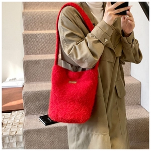 Gros plan sur le sac à bandoulière en peluche rouge vif avec texture douce et étiquette en cuir