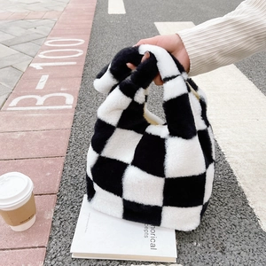 Gros plan du sac à main en peluche à damier noir et blanc dans un décor de rue