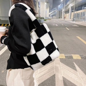 Lifestyle shot of thick plush checkerboard tote bag carried on a night city street