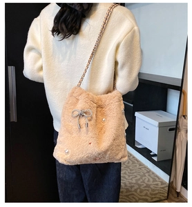 Détail du sac bandoulière en peluche avec nœud en strass et perles sur texture douce