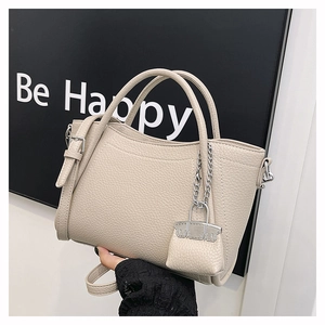 Minimalist beige lychee texture PU leather handbag with trapezoid shape and mini bag charm