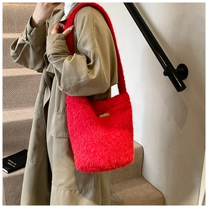 Détail du sac cabas en peluche rouge avec large bandoulière et patch en cuir