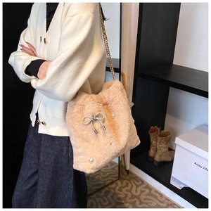 Détail du sac bandoulière en peluche beige avec nœud en strass et perles élégantes