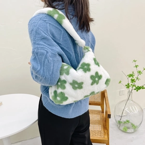 Detailed shot of white plush shoulder bag featuring green flower patterns and gold rings