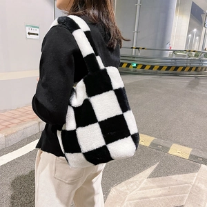 Detail of checkered plush tote bag shown on model in urban street setting at night
