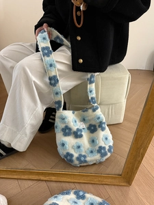 Detail view of plush shoulder bag featuring cream faux fur and blue floral pattern