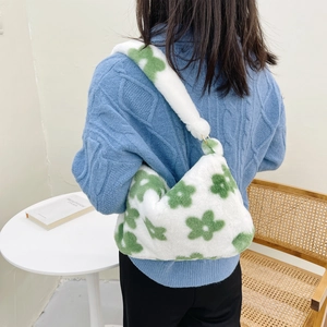 Detailed back view of a plush white shoulder bag with green floral patterns on a model