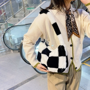 Close-up of black and white checkerboard plush shoulder bag on a female model