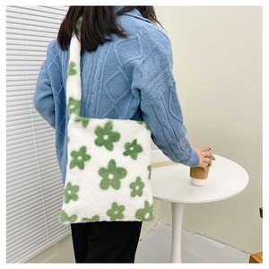 Détail du sac cabas en peluche blanc avec motif fleur verte porté à l'épaule