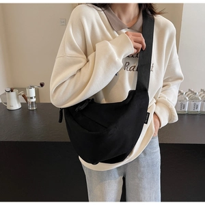 Minimalist black canvas crescent crossbody bag with adjustable wide strap and label