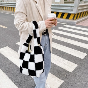 Détail d'un sac cabas en peluche à carreaux porté par un mannequin en style urbain chic