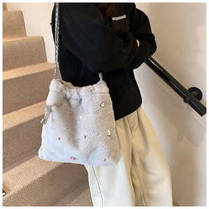 Sac bandoulière en fausse fourrure avec perles et strass porté par un mannequin en intérieur