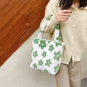 Close-up of soft white plush handbag featuring green floral patterns and fluffy texture