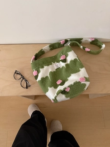 Detail of plush crossbody bag featuring green cloud pattern and pink floral accents