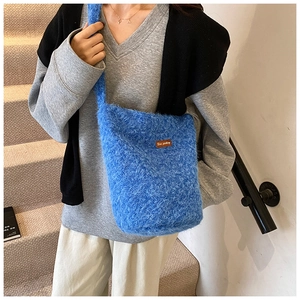 Gros plan détaillé du sac bandoulière en peluche bleue avec écusson en cuir brodé