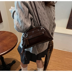 Close-up of dark brown crocodile-embossed baguette bag with a chocolate charm
