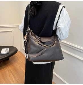 Detail view of large dark brown leather tote bag with elegant gold buckle on model shoulder
