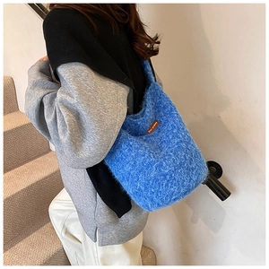 Détail du sac cabas bleu en peluche montrant la texture douce et l'étiquette logo