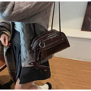 Detail of dark brown patent leather shoulder bag with cute dachshund and chocolate charms