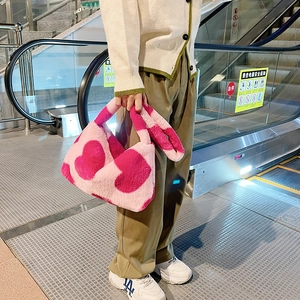 Détail du sac à main en peluche douce avec grands cœurs rose vif sur tissu rose clair