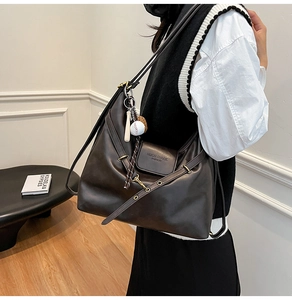 Detail of black large hobo bag with gold eyelets and stylish baseball keychain charm