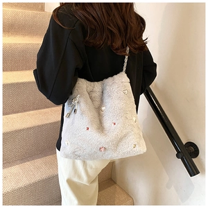 Détail du sac à main en peluche gris clair avec perles et nœud en cristal