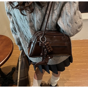 Close-up of glossy brown PU leather Boston bag with chocolate and puppy charms