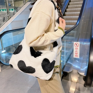 Détail de la texture en peluche blanche avec des motifs de cœur noirs sur le sac à bandoulière