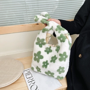 Dettaglio della borsa in peluche bianca con motivi floreali verdi e fodera dorata