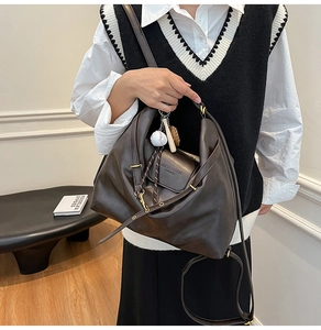 Close-up of dark brown vintage backpack with textured leather and baseball charm