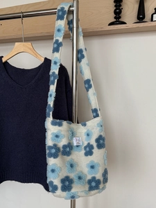 Detail of plush off-white shoulder bag with 3D blue floral patterns and JJ JIAN label