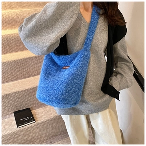 Détail du sac bandoulière en fausse fourrure bleue avec texture douce et logo en cuir