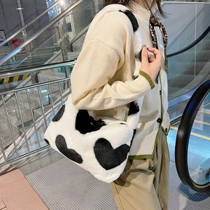 Détail du sac à bandoulière en peluche blanche avec motifs de cœurs noirs porté