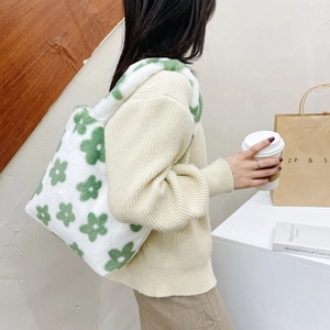 Detailed view of white plush tote bag with green floral pattern worn by a model