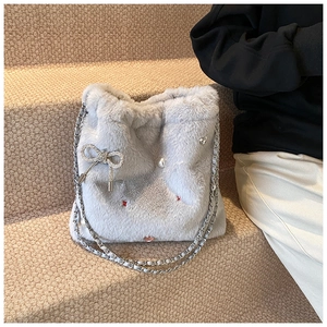 Vue détaillée du sac seau bleu clair en peluche avec nœud en perles et bandoulière chaîne
