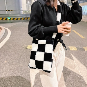Chic black and white checkerboard plush crossbody bag shown in an outdoor street style look