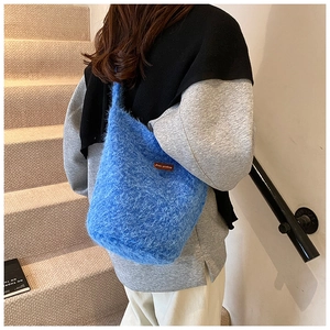 Détail du sac fourre-tout en maille peluche bleue montrant la texture douce et l'étiquette