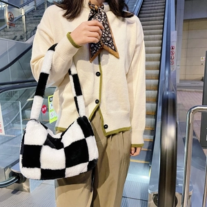 Detail of checkered plush shoulder bag shown in a real-life commuting scene on an escalator