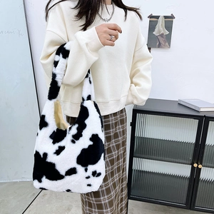 Close-up detail of plush cow print tote bag made of soft faux fur with white wall backdrop